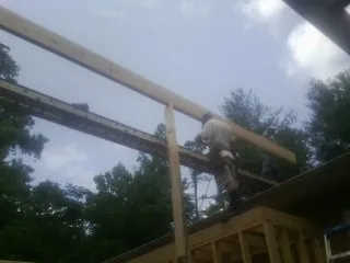 Carpenter setting a ridge beam over a new addition frame — Ice Dam Removal by Roofing Brothers in Crystal Beach