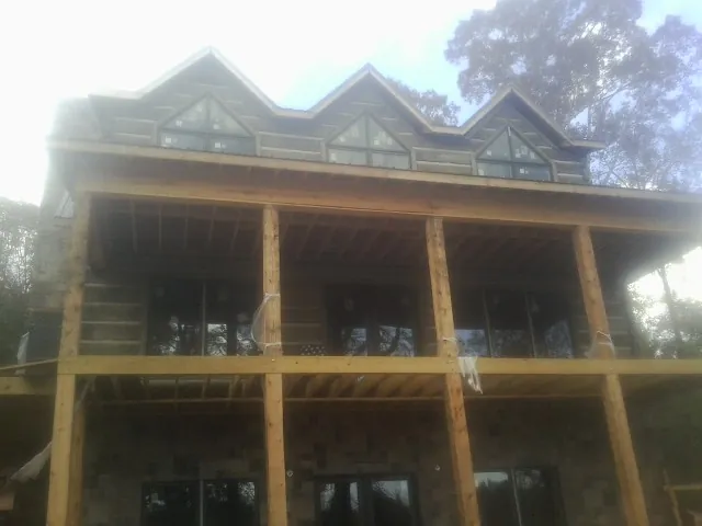 Dormers and porch framing on a large log home under construction — Roof Coating work by our crew in Crystal Beach