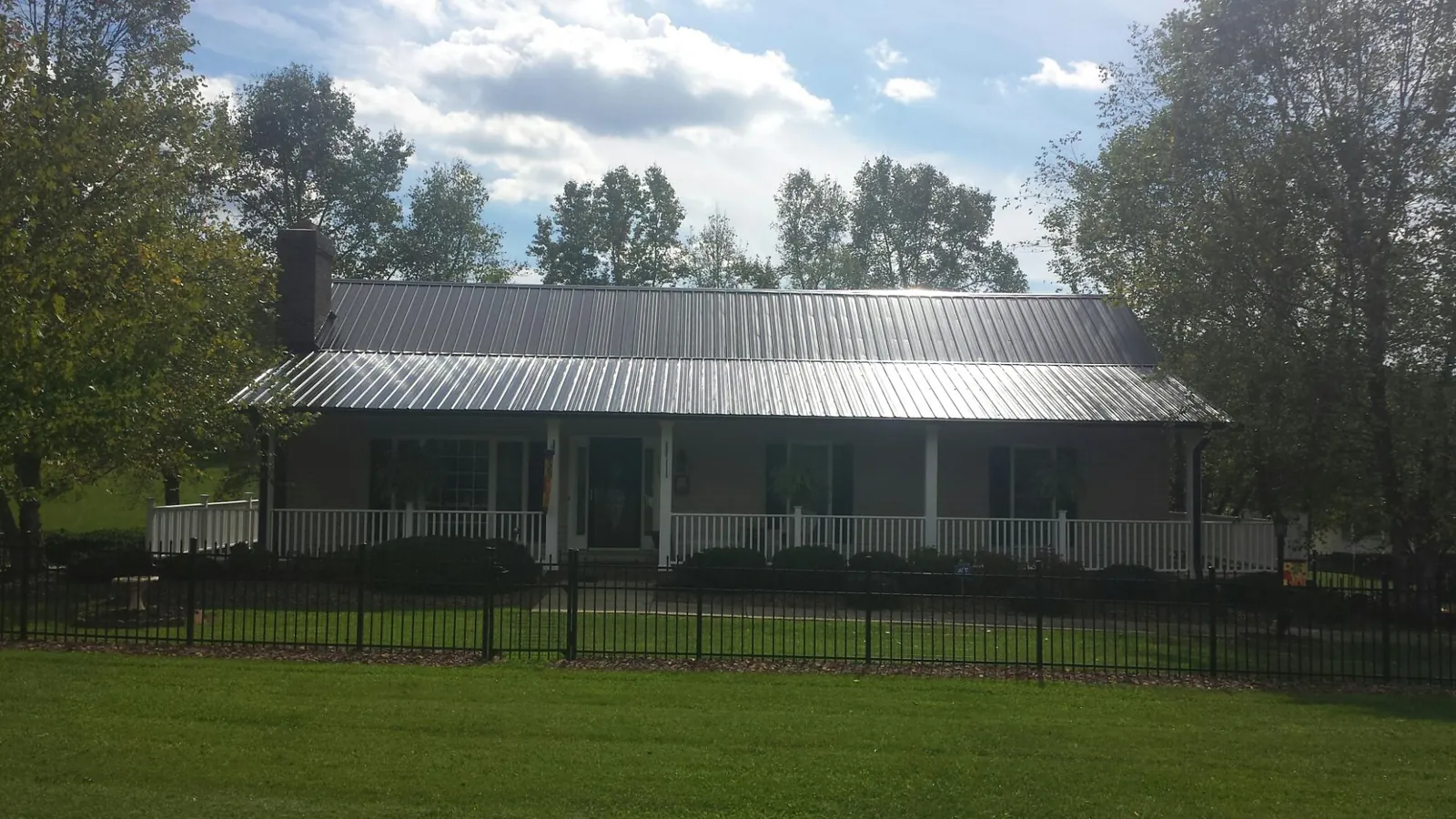 Gray metal roof on a brick ranch with a full width front porch — Gutter Guard Installation work by our crew in Crystal Beach