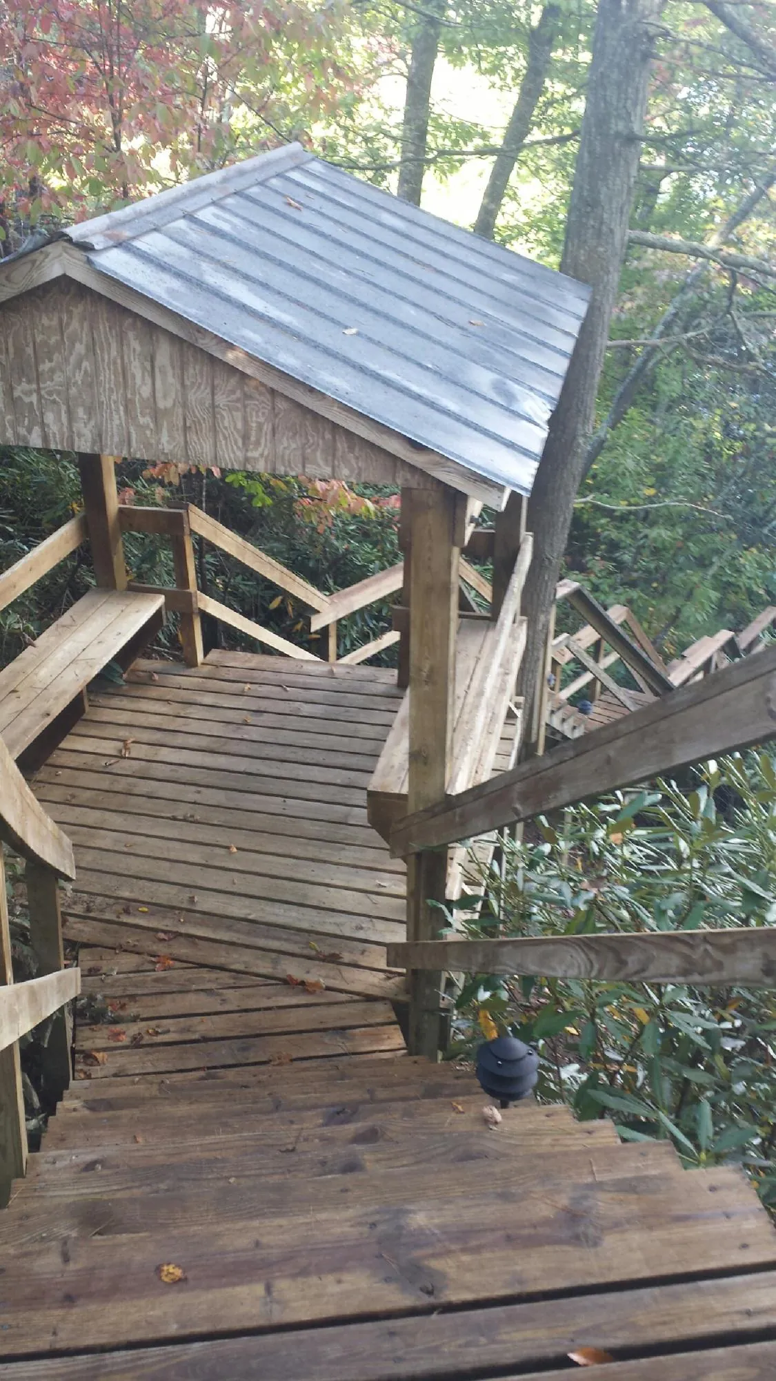 Metal roofed shelter over wooden steps on a wooded walkway — Skylight Repair & Installation work by our crew in Crystal Beach