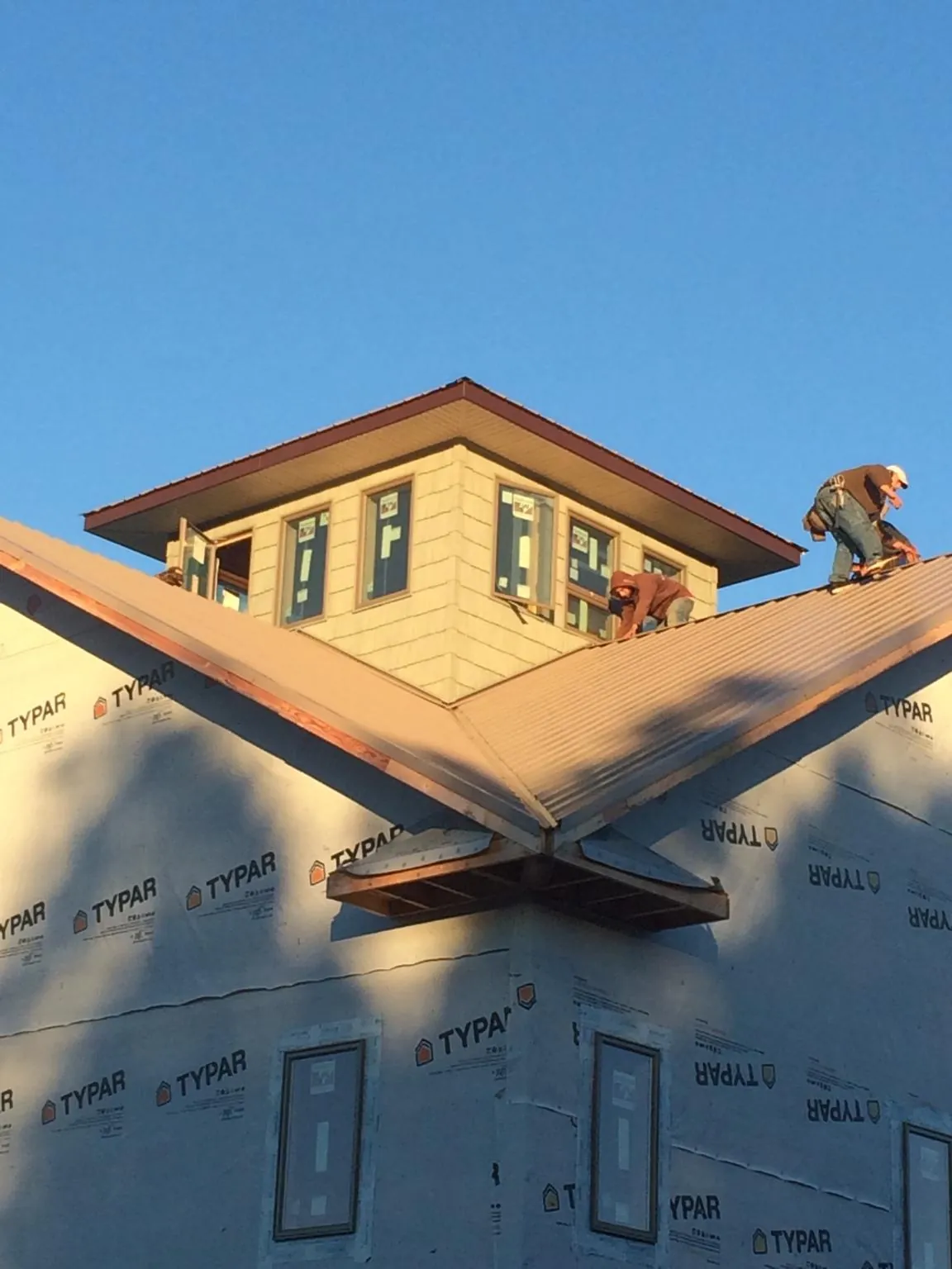 Roofers working around a rooftop cupola on a new metal roof at sunset — Roof Waterproofing in Crystal Beach by Roofing Brothers